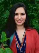 Destinee Smiling at the camera with a orange and blue blouse and an orange blazer on. 